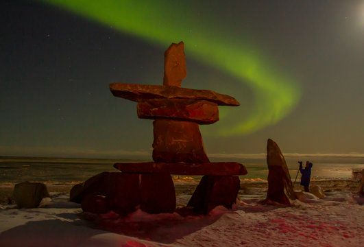 Northern lights and inukshuk with tourist