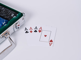Game cards. Four cards, four aces, four symbols in background and white table and poker chips briefcase in the frame.
