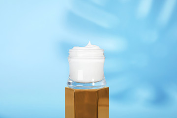 Open jar of cream on display against blue background