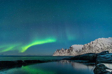 Fototapeta na wymiar Northern lights, Aurora Borealis, Devil Teeth mountains in the background, Tungeneset, Senja, Norway