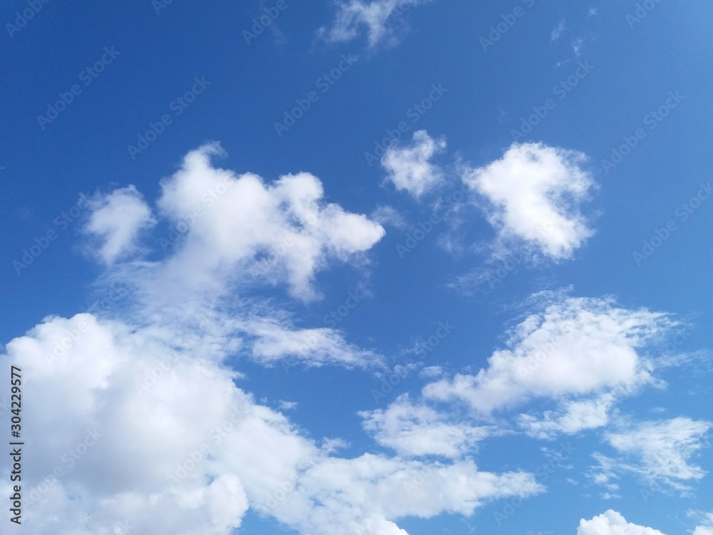 Wall mural light fluffy white clouds against blue sky on a sunny day