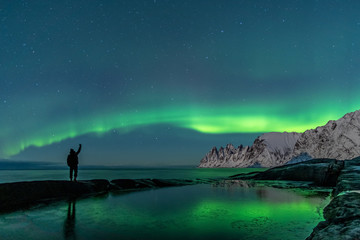 Fototapeta na wymiar Man watching the northern lights, Aurora Borealis, Devil Teeth mountains in the background, Tungeneset, Senja, Norway