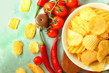 Plate with tasty potato chips, chili pepper and tomatoes on table