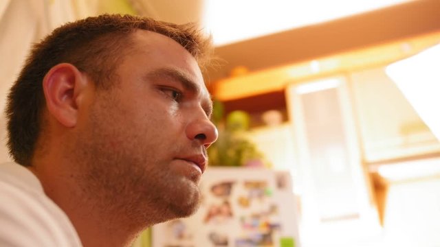 Portrait of a man smiling and sitting at home in the kitchen. Сlose up shot.