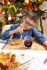 Chłopiec w okularach siedzi przy stole i nabija na widelec jedzenie leżące na talerzu. Pięknie...