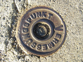 Vermessungspunkt - survey point. A survey point is mounted on asphalt for measurements on the ground.