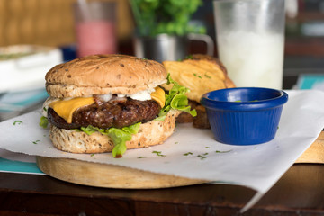 Real hamburger, served in restaurant, without editing, served on wooden board with lettuce and mayonnaise, french fries and frozen lemon.