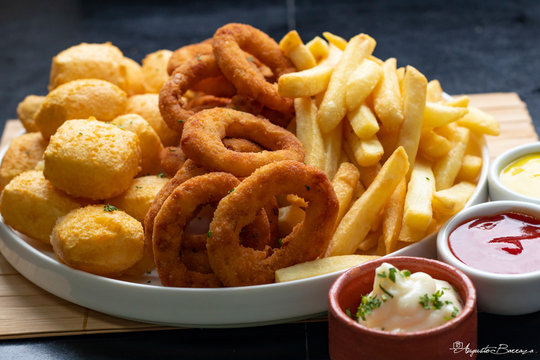 Por&ccedil;&atilde;o mista frita em prato branco redondo com molhos,  Mixed portion with fritras, cassava and onion