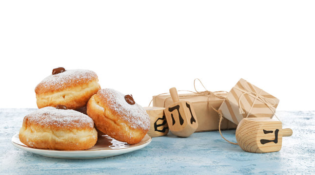 Donuts for Hanukkah, gifts and dreidels on table against white background