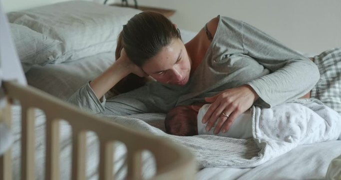 Authentic shot of new mother is breastfeeding and caressing her newborn baby in a nursery in a morning. 