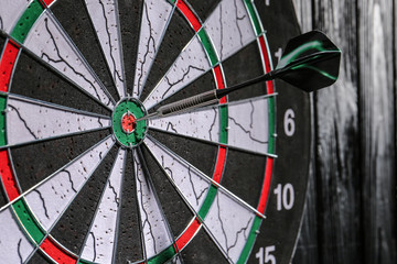 Dartboard with hit bullseye hanging on wall, closeup