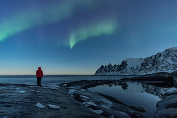 Woman watching the northern lights, Aurora Borealis, Devil Teeth mountains in the background, Tungeneset, Senja, Norway