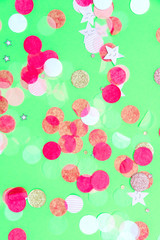 Fototapeta na wymiar Multicolor pink, gold and white confetti on the bold minty green background, holiday celebration backdrop, Flat lay style