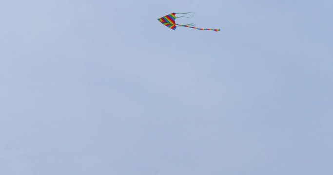 Colorful kite flying in blue sky. Toy for fun and leisure activity and recreation.