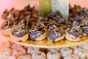 Mimi eclair donuts with chocolate candy on gold cake tower