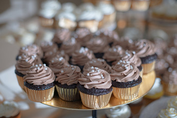 Chocolate cupcakes with chocolate frosting and pearl srinkles in gold paper cuos
