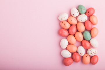 Fototapeta na wymiar Colorful multicolored chocolate eggs candies on a pink pastel background. copy space, top view.