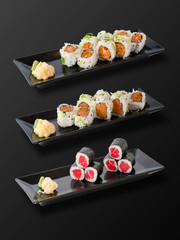 Isolated on black background of Set of Sushi Rolls in black plate. Clipping Path Included.