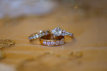 Gold bride and groom wedding rings with round diamonds on beige table cloth