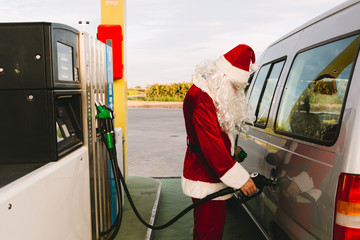 Santa Claus fueling up in his car in a petrol station