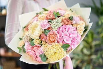 European floral shop. Beautiful bouquet of mixed flowers in womans hands. the work of the florist at a flower shop. Delivery fresh cut flower.