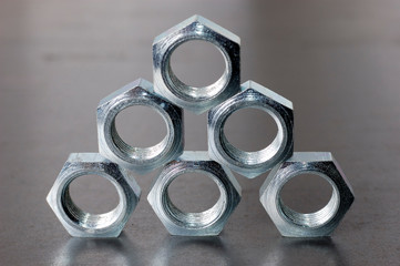 Close-up of a pyramid of five chrome metal nuts