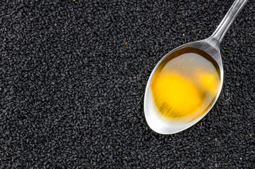 Black cumin seeds essential oil , Nigella Sativa in spoon on heap of black cumin. Organic herbal...