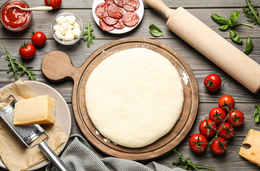 Flat lay composition with dough and fresh ingredients for pepperoni pizza on wooden table - obrazy, fototapety, plakaty