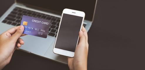 A close up of a credit card in your hand and smartphone Laptop background Purchase concept Online products The concept of service payment through application. Copy Space for text.