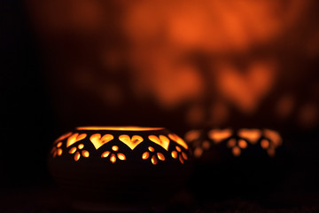 Decorative ceramic lanterns with heart cutouts lit by glowing candles