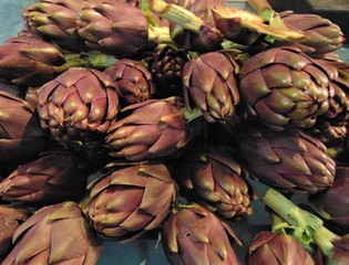 Obraz premium Artichokes for sale at the market. Fresh purple ripe artichokes at the vegetable market, Italia. Background, Close-up.