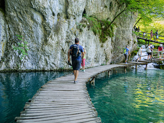 Turista paseando en una plataforma rodeada de agua verdosa en el Parque Nacional de Plitvice en Croacia, verano de 2019