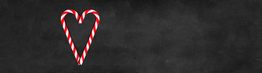 Sweet candy canes heart isolated on black concrete texture - christmas valentine background...