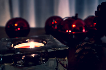 Christmas candles, red apples, cones and spices on rustic wooden background with  Balls and Christmas lights. Close up, selective focus 