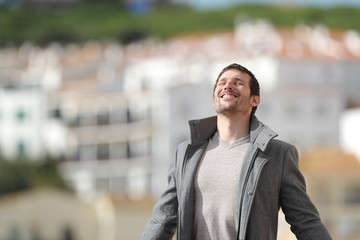 Happy adult man breaths deeply fresh air in a town in winter