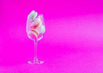Macaroons french cookies in a glass goblet on a pink background. Minimalistic concept. Copy space.