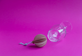 Christmas handmade wooden toy near the glasses goblet on a pink background. Minimalistic concept. Copy space.
