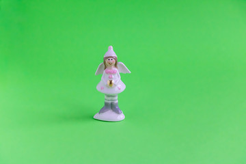 Christmas figurine of a cute angel with a golden heart on a green background. Congratulations to...