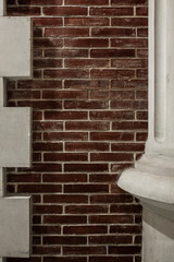 Fragment of a white column on a background of a red brick wal