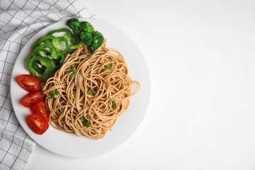 Tasty buckwheat noodles with fresh vegetables served on white table, flat lay
