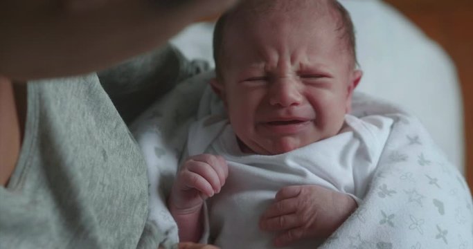Authentic shot of neo mother is keeping in arms and caressing her newborn baby  while is crying in a nursery in a morning.