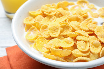 Tasty corn flakes with milk on white table, closeup