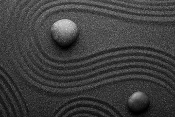 Foto auf Acrylglas Steine im Sand Schwarzer Sand mit Steinen und schönem Muster, flach gelegt. Zen-Konzept