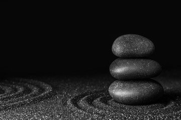 Fototapeta na wymiar Black sand with stones and beautiful pattern against dark background. Zen concept