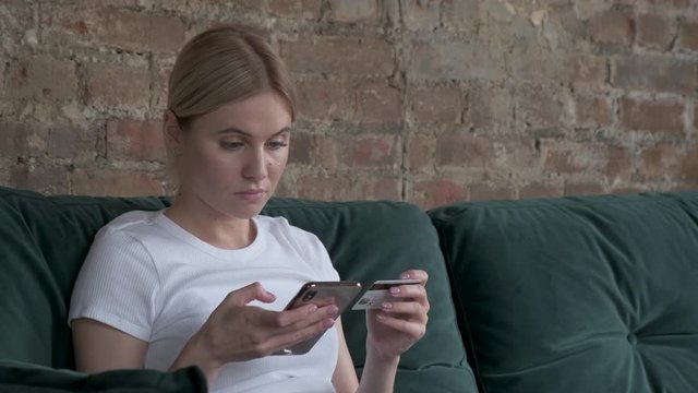 Online banking with smart phone. Woman buys online shopping at home with credit card and smartphone. Woman type entering master card number books. Girl putting debit or credit card 