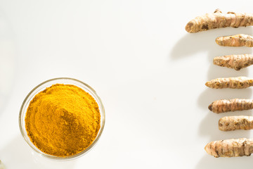 Stack of turmeric powder and turmeric rhizomes separate on a white background