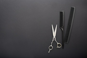 Flat lay composition with Hairdresser tools: scissors, combs, hair iron on black background with copy space for text. Frame. Hairdresser service. Beauty salon service. Hairdresser Set.