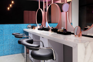 Interior of luxury stylish beauty salon. chairs and table with cosmetics for makeup .Pink concept design.