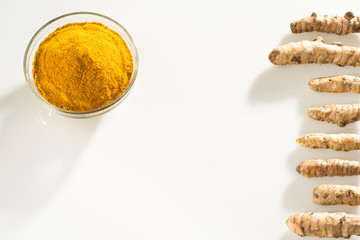 Stack of turmeric powder and turmeric rhizomes separate on a white background