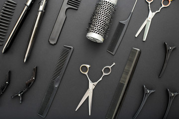 Flat lay composition with Hairdresser tools: scissors, combs, hair iron on black background. Frame. Hairdresser service. Beauty salon service. Hairdresser Set.